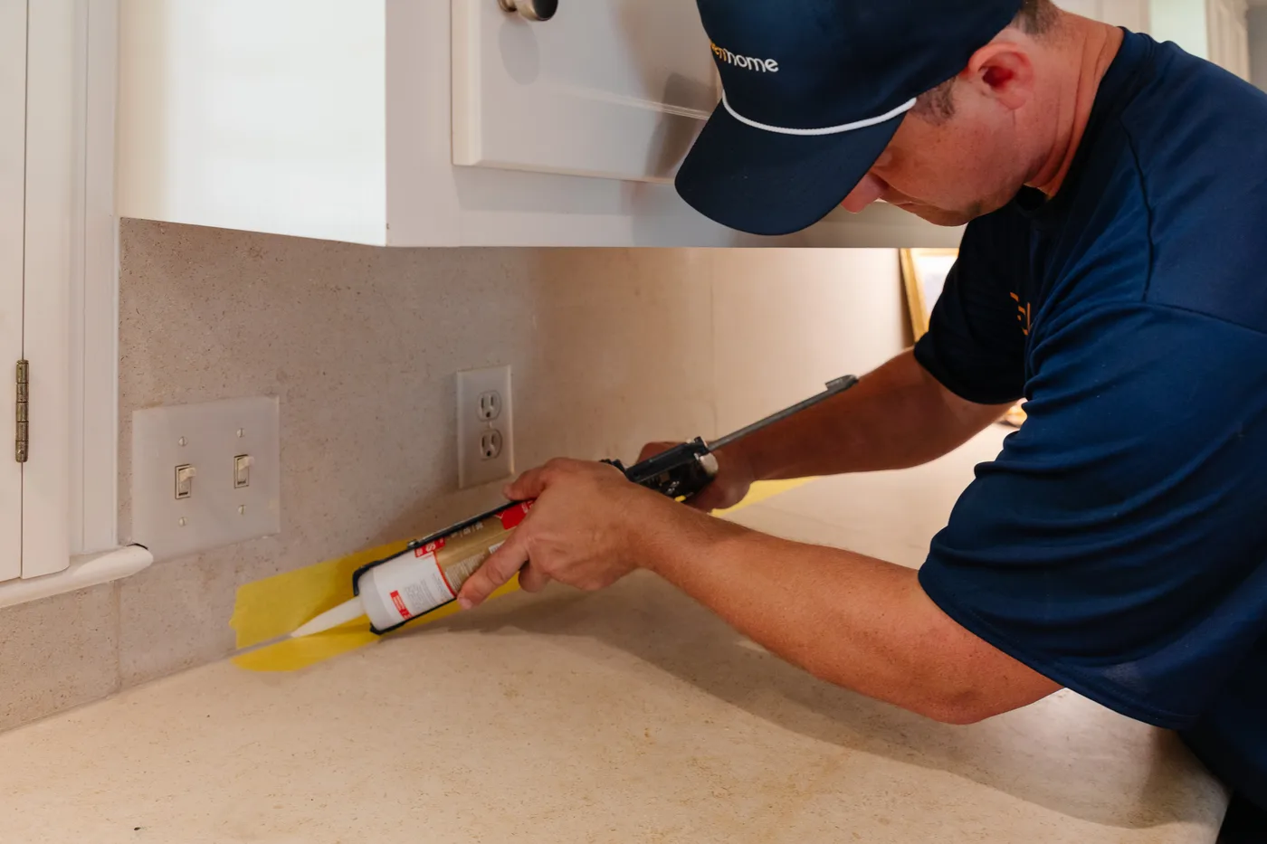 GoldenHome technician recaulking a kitchen countertop near the sink in a Topeka home